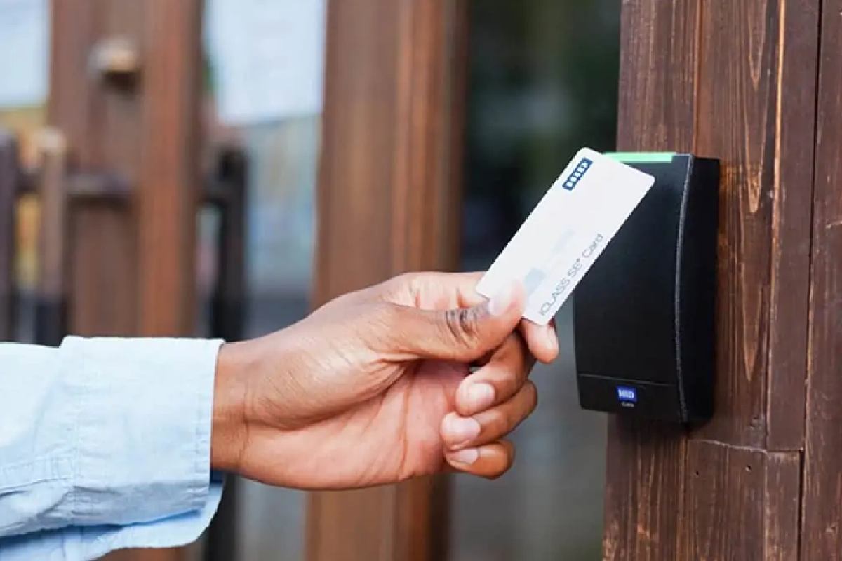 An human hand with RFID card on door lock reader.